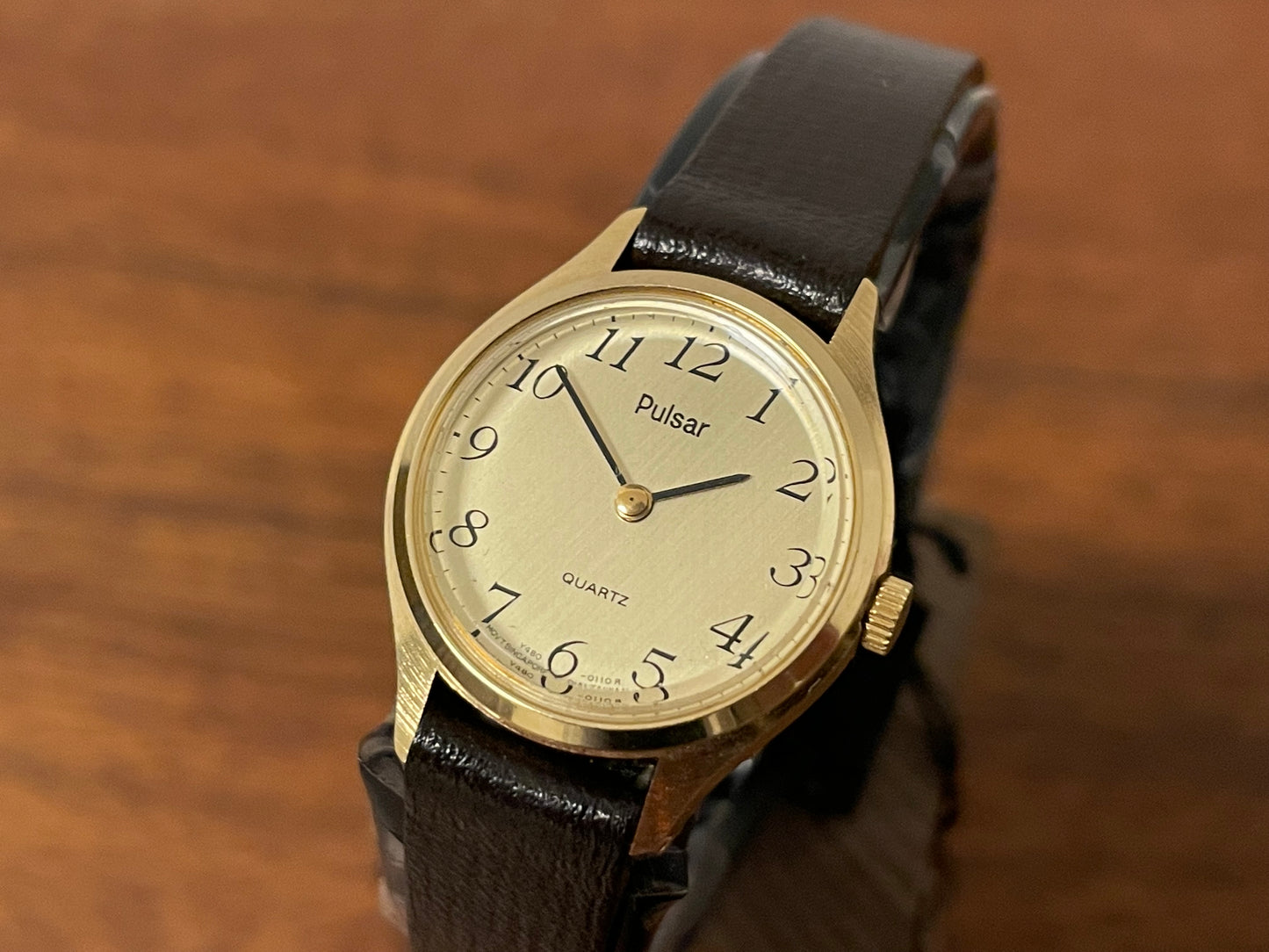 (1990) Pulsar Y480-0060 dress watch - gold colored case - champagne dial w/ black Arabic numerals - small size (NOS)