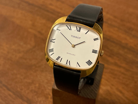 Front side (1970s) Tissot Stylist manual-wind dress watch - gold colored case - white dial w/ black Roman numerals (NOS)