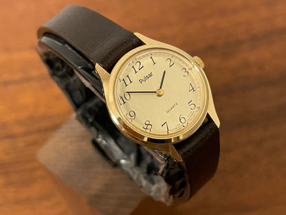(1990) Pulsar Y480-0060 dress watch - gold colored case - champagne dial w/ black Arabic numerals - small size (NOS)