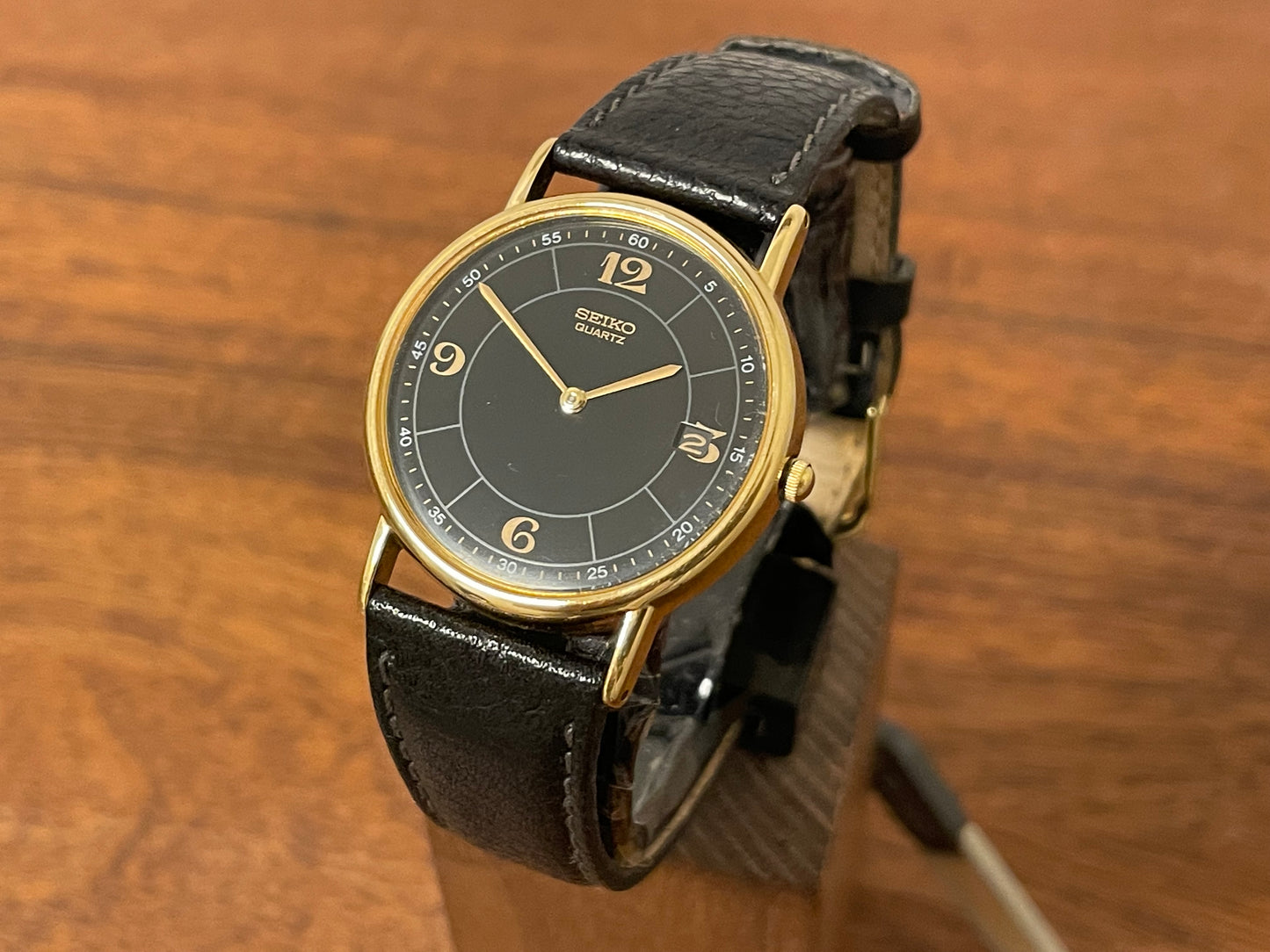 Front side (2000) Seiko 5Y39-7010 dress watch - gold colored case - black dial w/ flat gold Arabic numerals (NOS)