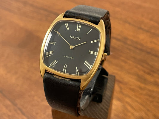 Front side (1970s) Tissot Stylist manual wind dress watch - gold colored case - black dial w/ gold Roman numerals (NOS)