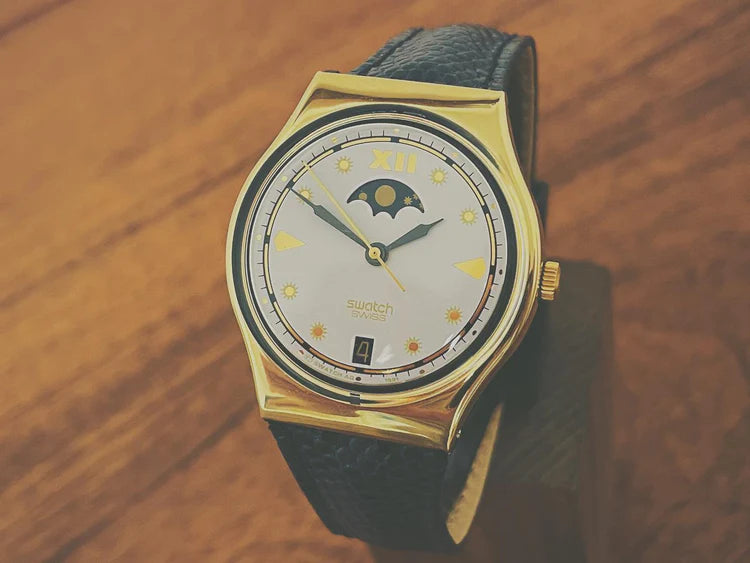 Front view of gold colored Swatch watch with moon phase complication