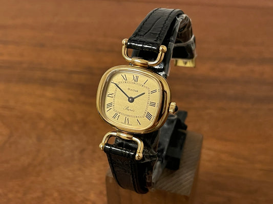 Front side (1980s/1990s) Bulova Paris dress watch - cushion case - gold dial w/ black Roman numerals - small size (NOS)