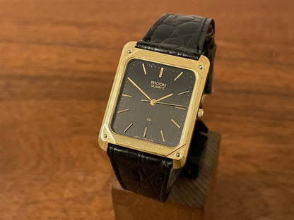 Front side (1970s/1980s) Ricoh 702009 quartz "Tank" dress watch - black dial w/ gold markers (NOS)