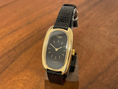 Front side (1979) Timex 100 manual wind dress watch - Swiss made - tonneau case - black dial w/ gold markers