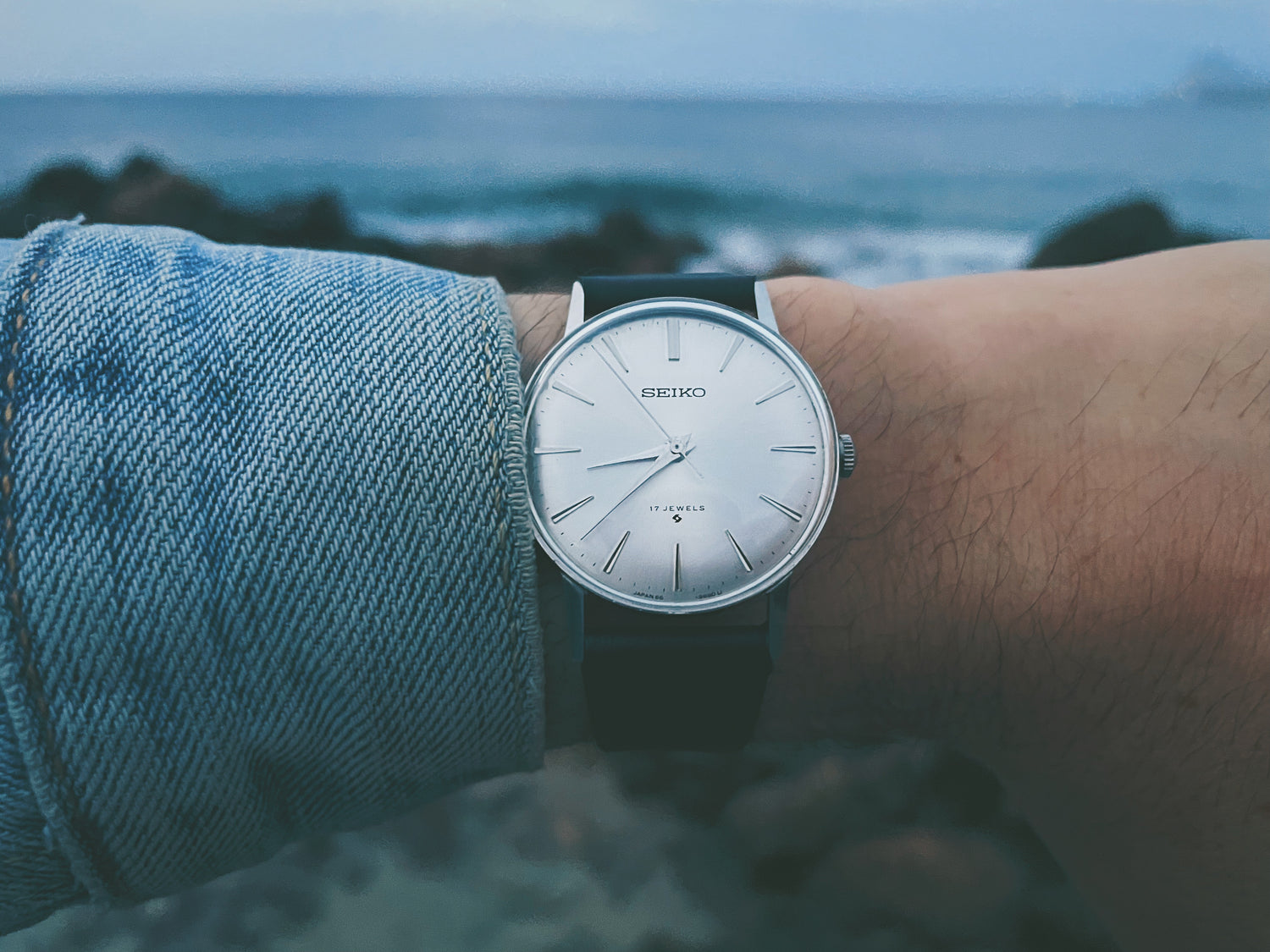 Close-up shot of Seiko watch on wrist with waves on the background