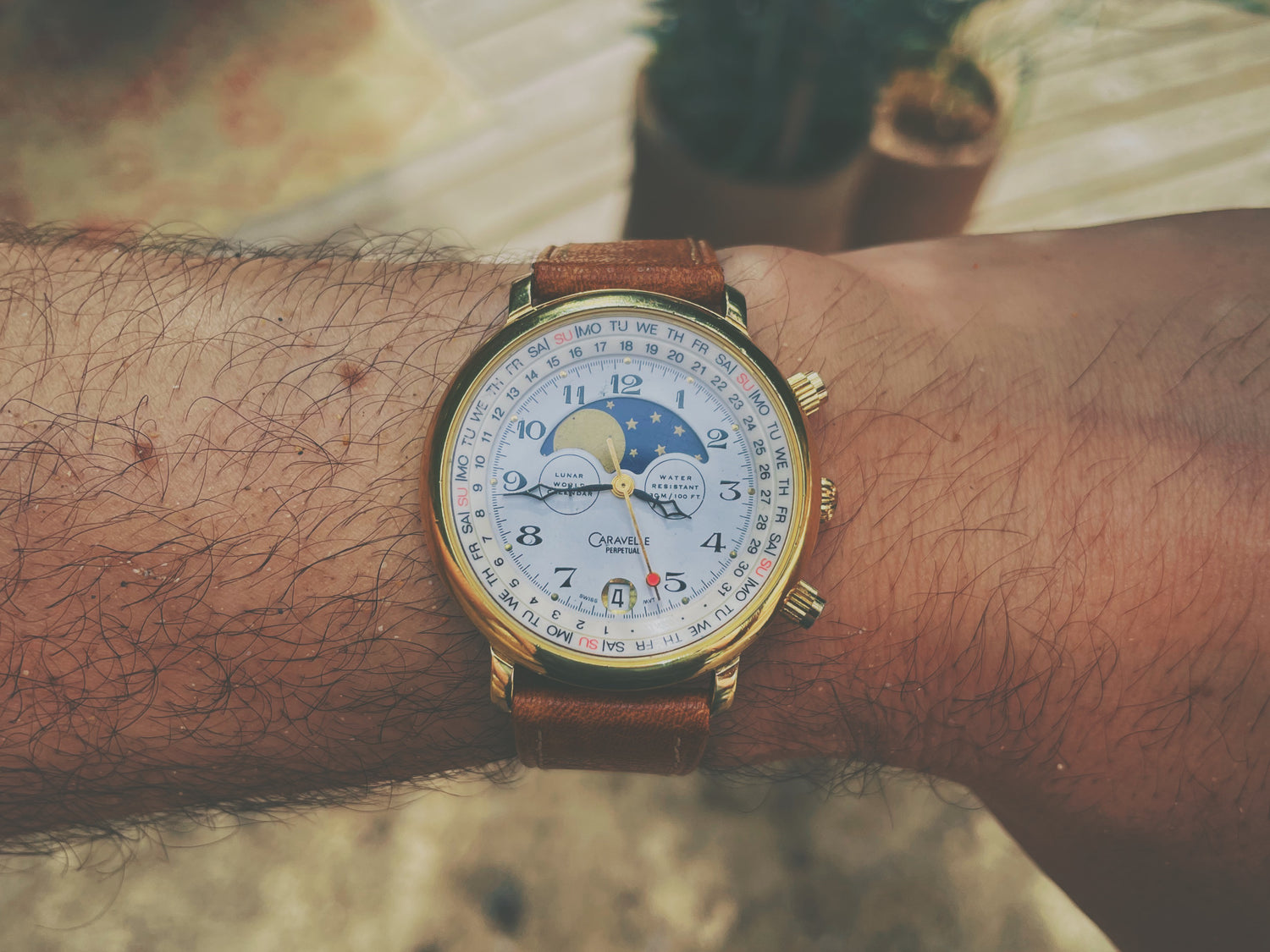 Close-up shot of vintage gold Caravelle watch on wrist with sand in the background