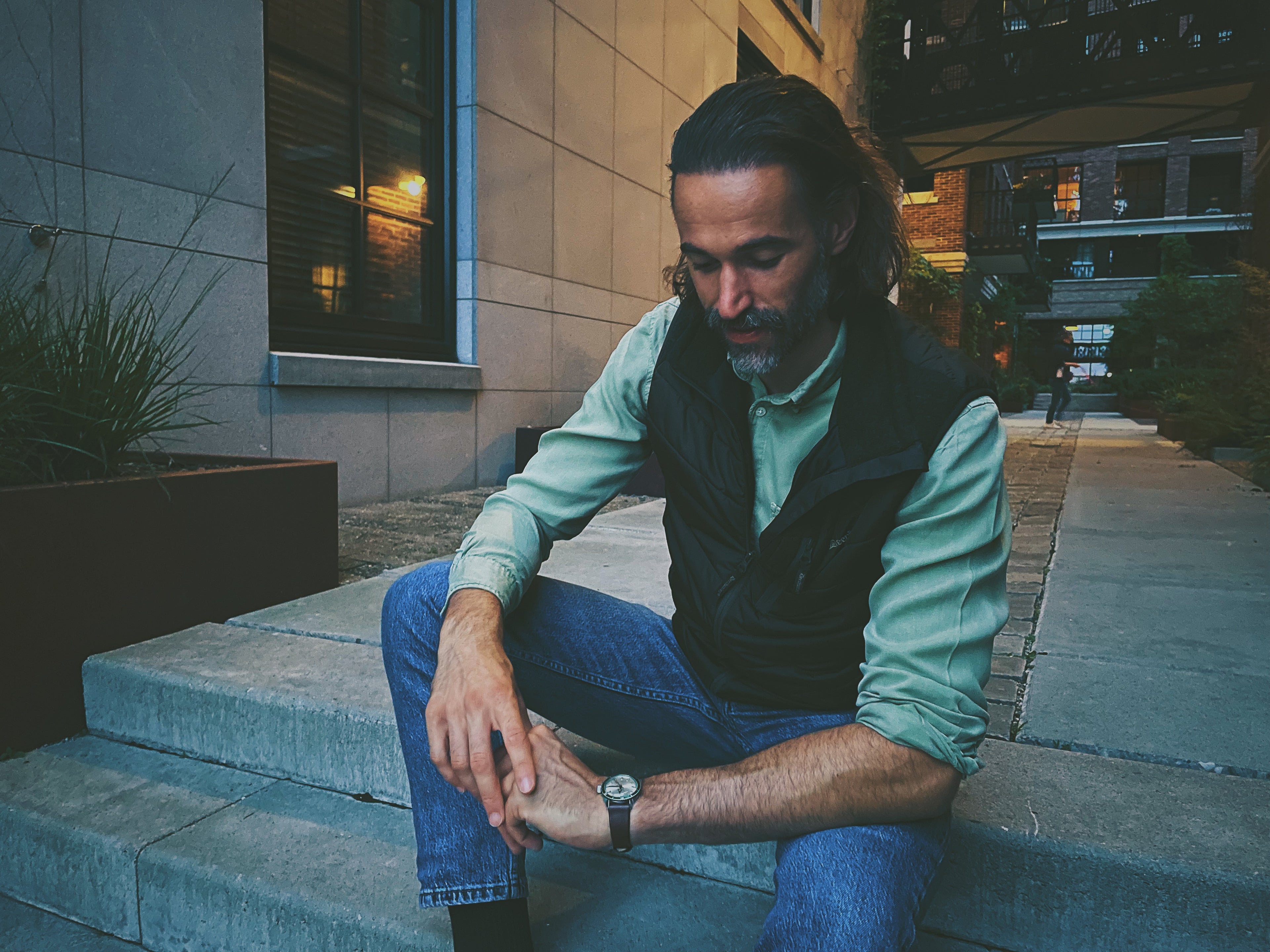 Man sitting on steps, looking at his vintage wristwatch