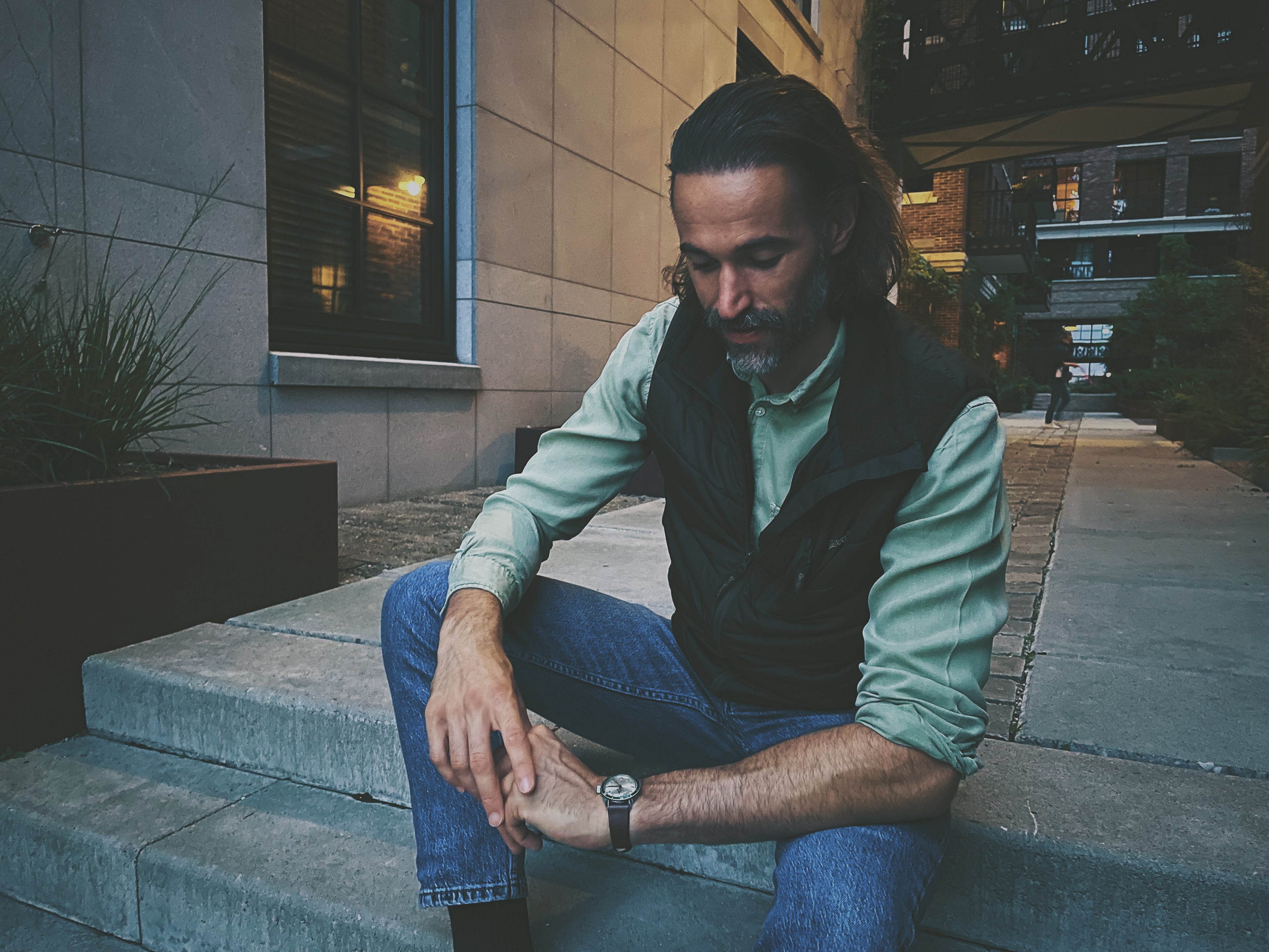Man sitting on steps looking at his vintage wristwatch